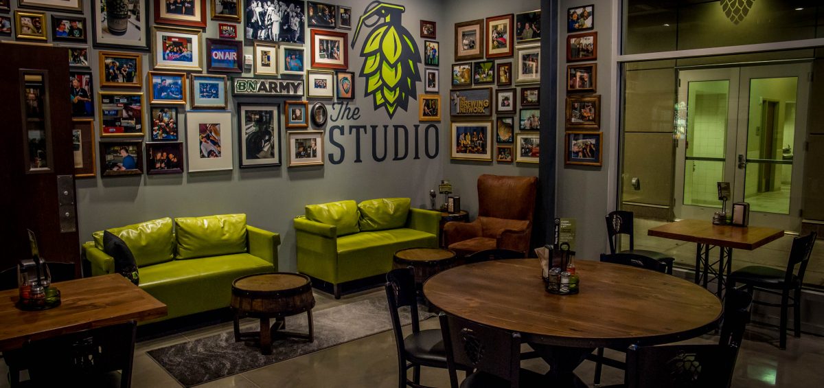 Hop Grenade Fort Collins Studio with pictures on the wall, green couches and wooden tables
