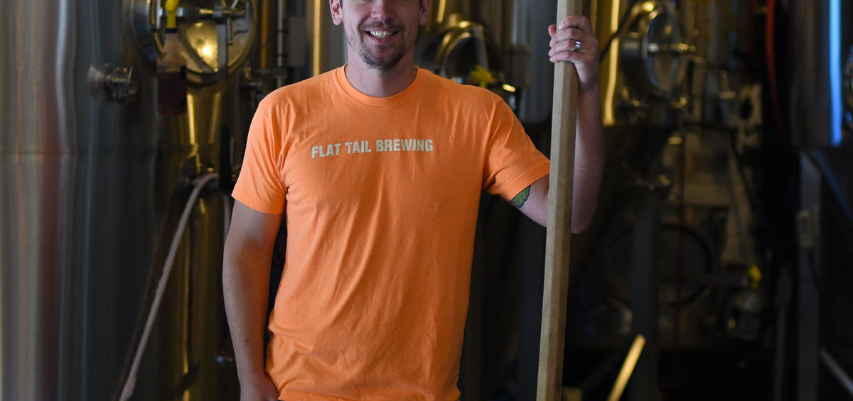 Dave Marliave of Flat Tail Brewing holding mash paddle in front of fermentors
