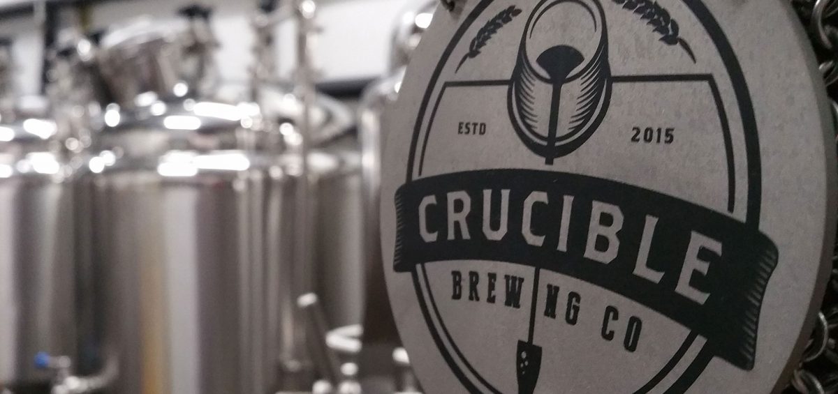 Crucible Brewing logo with brewery in background