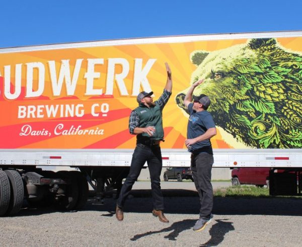 Sudwerk Brewing Company guys jumping to high five in front of truck